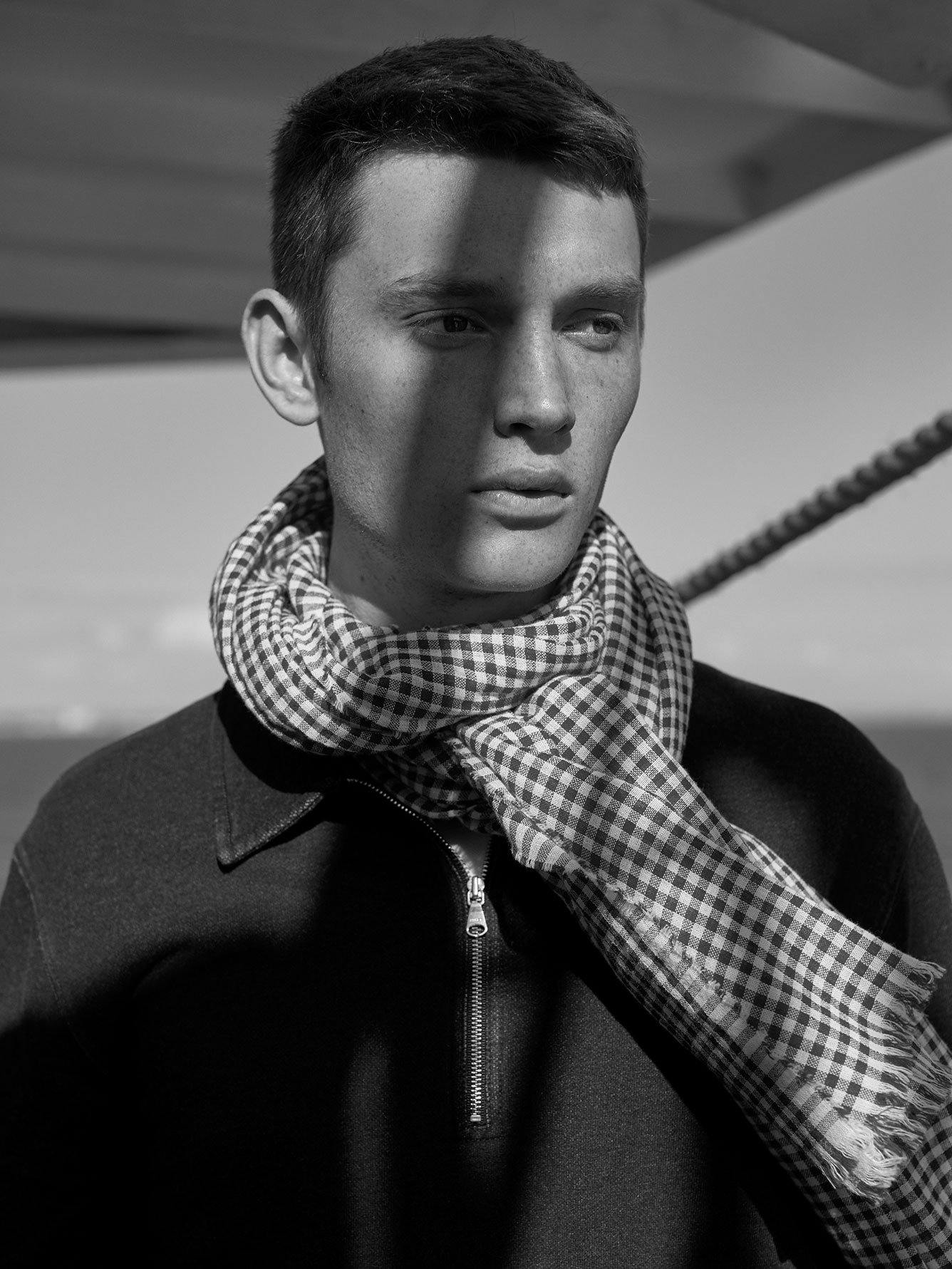 Black and white photo of male model wearing black and white gingham scarf